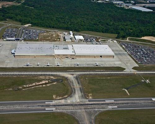 Aerial view of Gulfstream Service Center. Rectangular building surrounded by parking lots and parked aircraft.